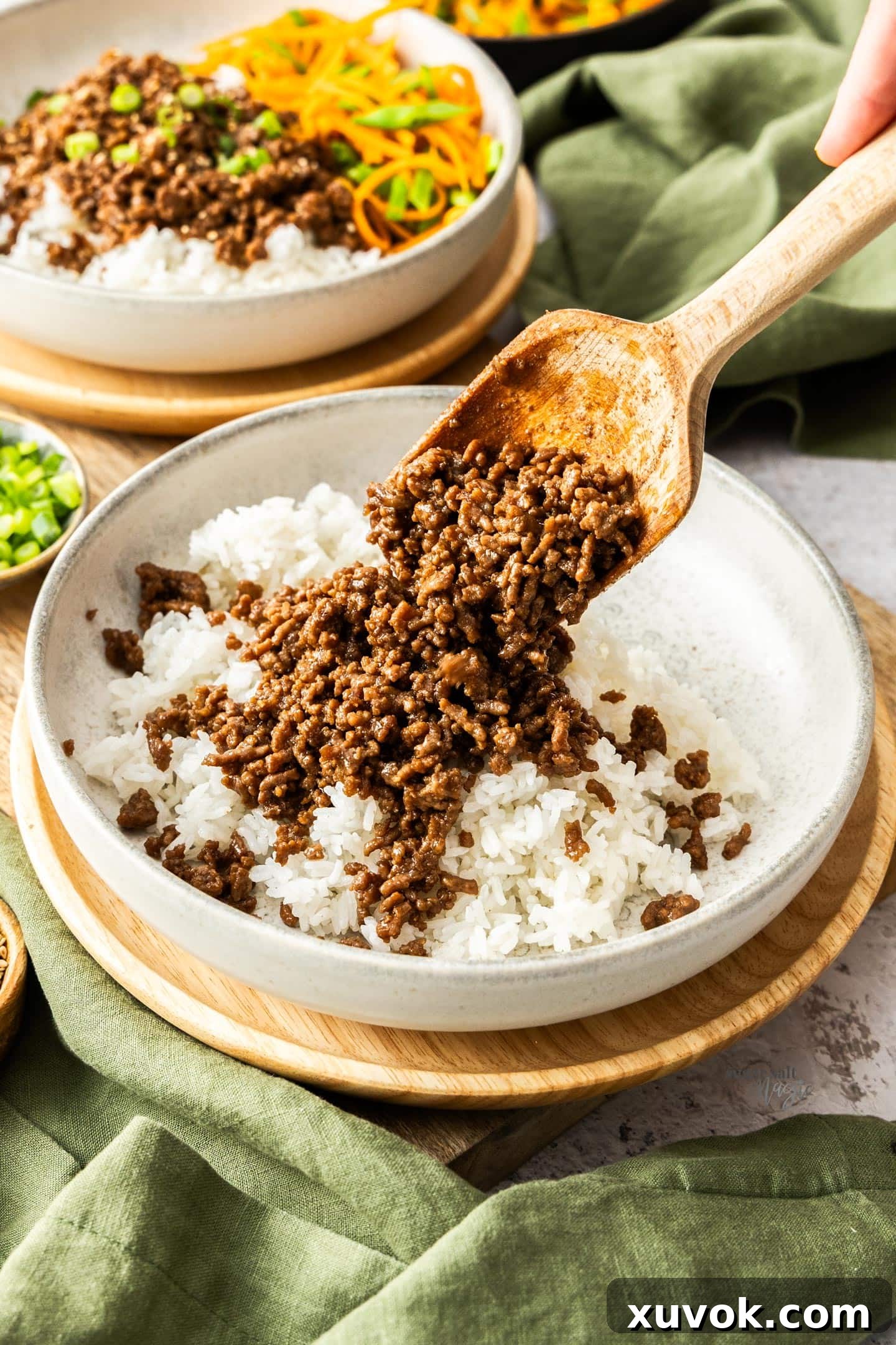 A wooden spoon spooning the beef over rice.
