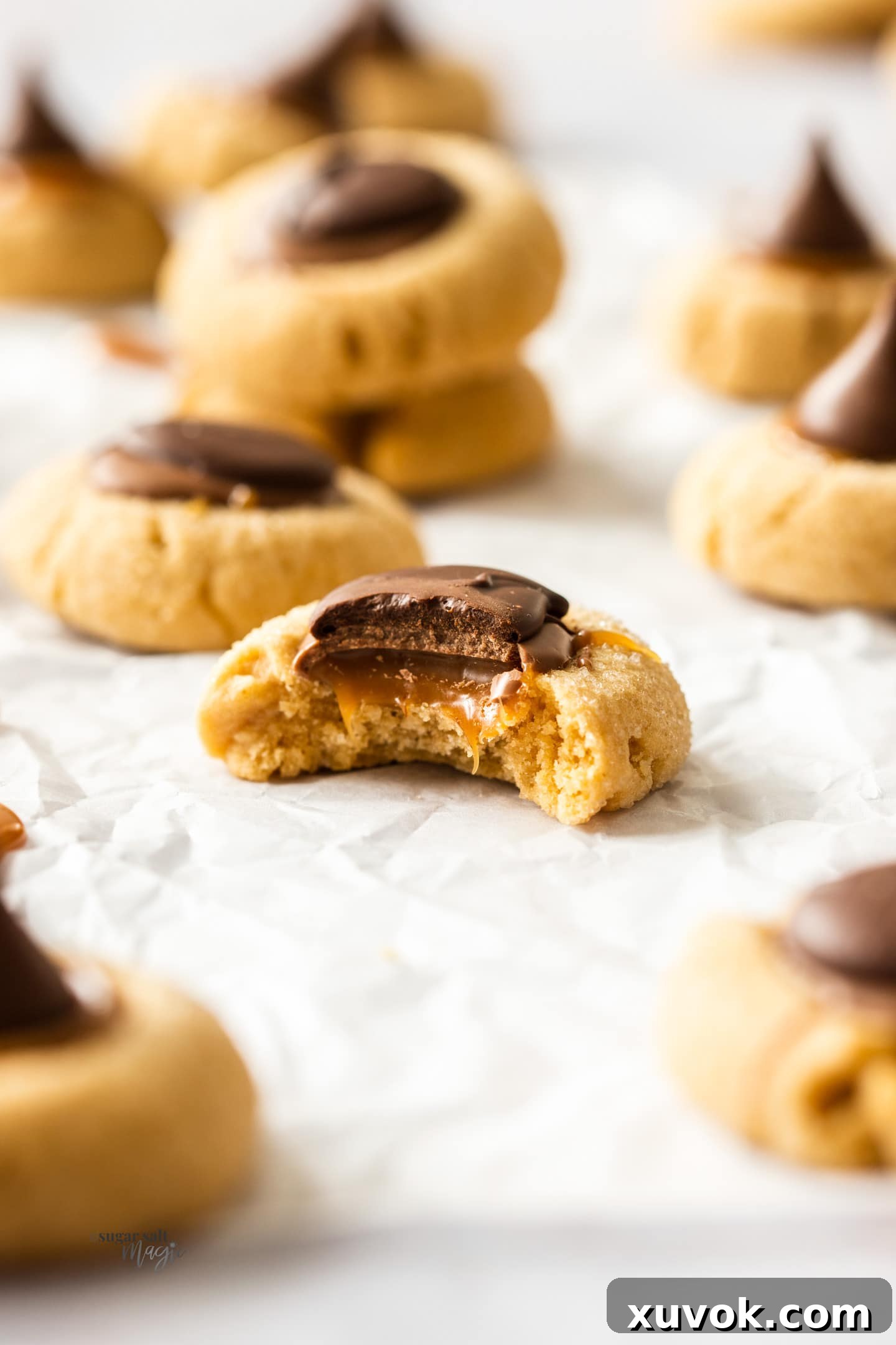 A Caramel Peanut Butter Thumbprint Cookie with a bite taken out to show the gooey caramel inside.
