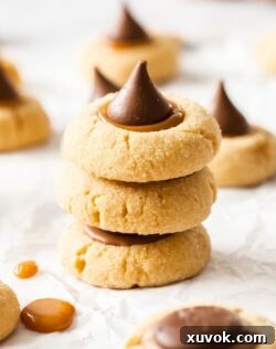 A stack of 3 thumbprint cookies with the top one adorned with a Hershey's Kiss.