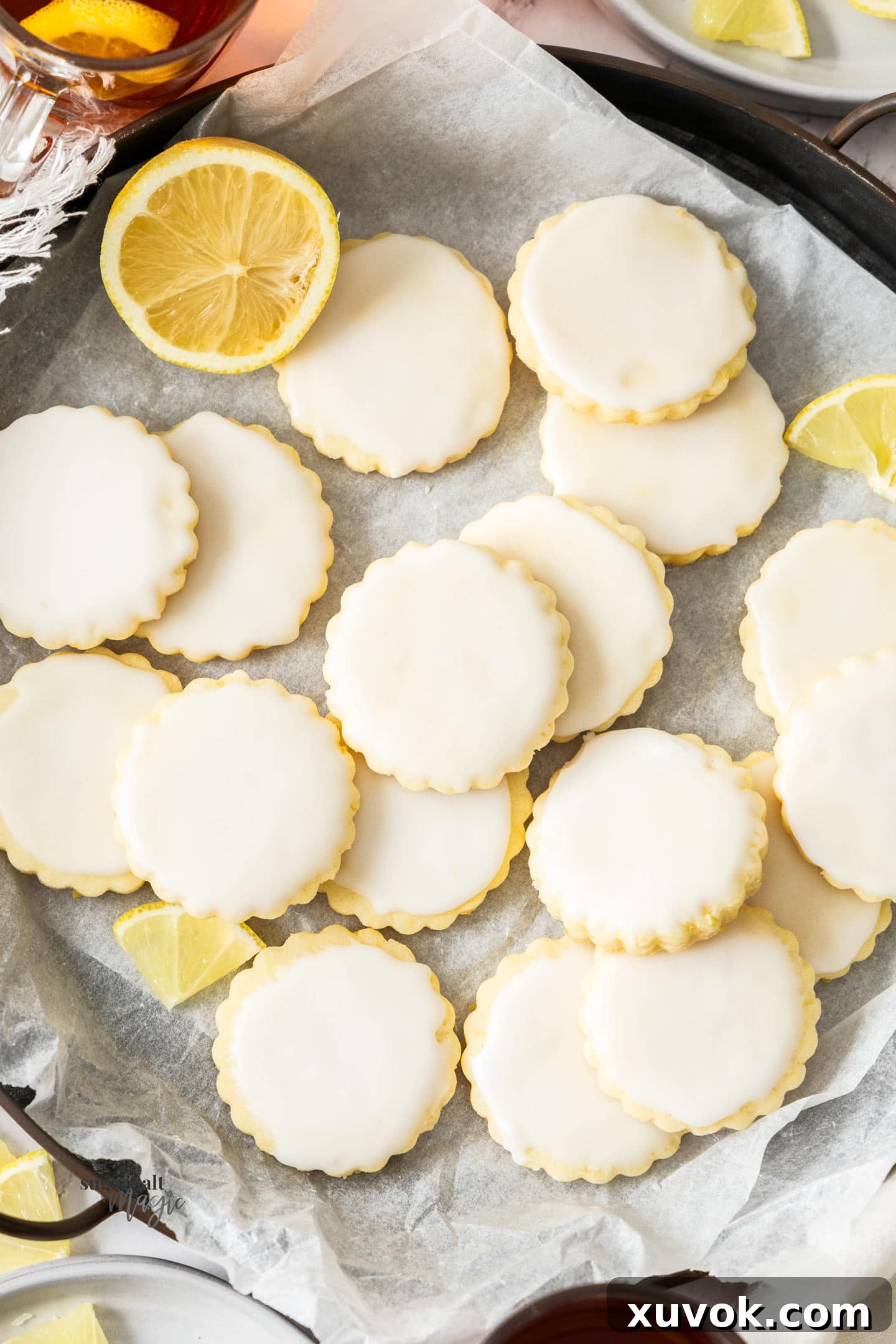 A top-down view of a fresh batch of perfectly iced lemon sugar cookies, arranged beautifully on a cooling rack, showcasing their soft, pale yellow centers and vibrant lemon glaze. Each cookie promises a buttery, zesty bite, making them an ideal treat for any occasion.