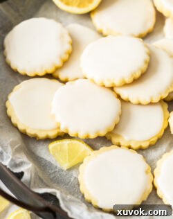 Closeup of a pile of glistening lemon iced cookies, highlighting their soft texture and the vibrant, sweet glaze.
