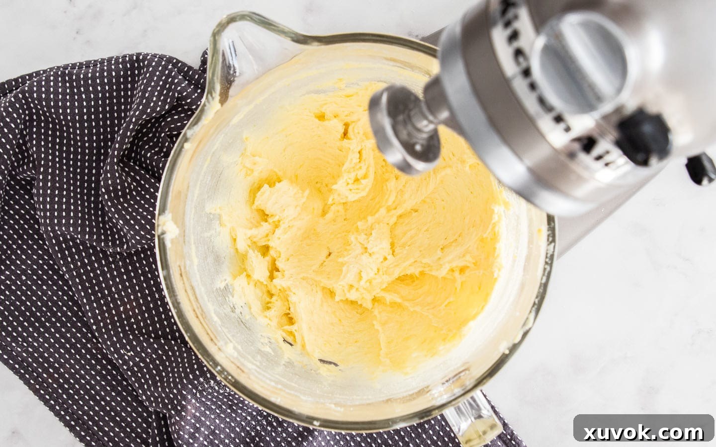 The creamy mixture in a stand mixer bowl after the egg and vanilla extract have been added and fully incorporated, showing a smooth and cohesive consistency.