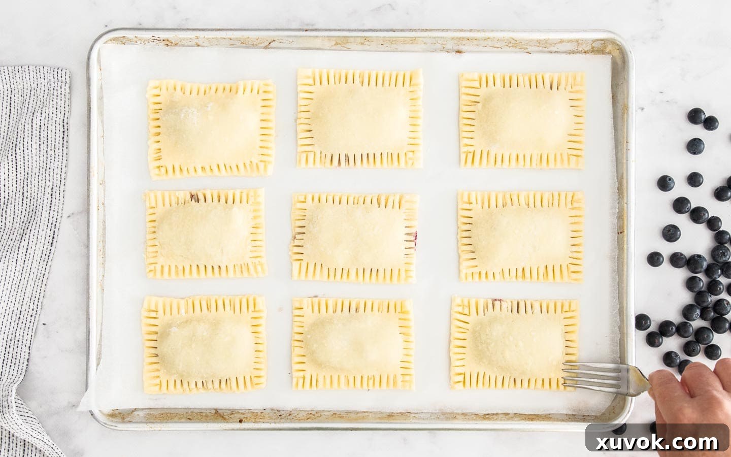 A close-up of a pop tart being sealed with a fork, creating the classic crimped edge.