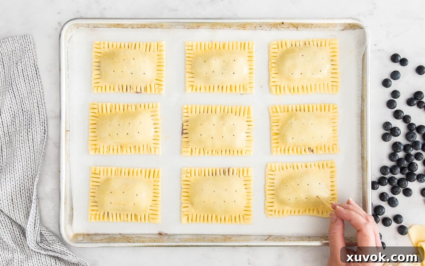 A toothpick being used to create small steam vents in the top crust of an unbaked pop tart.