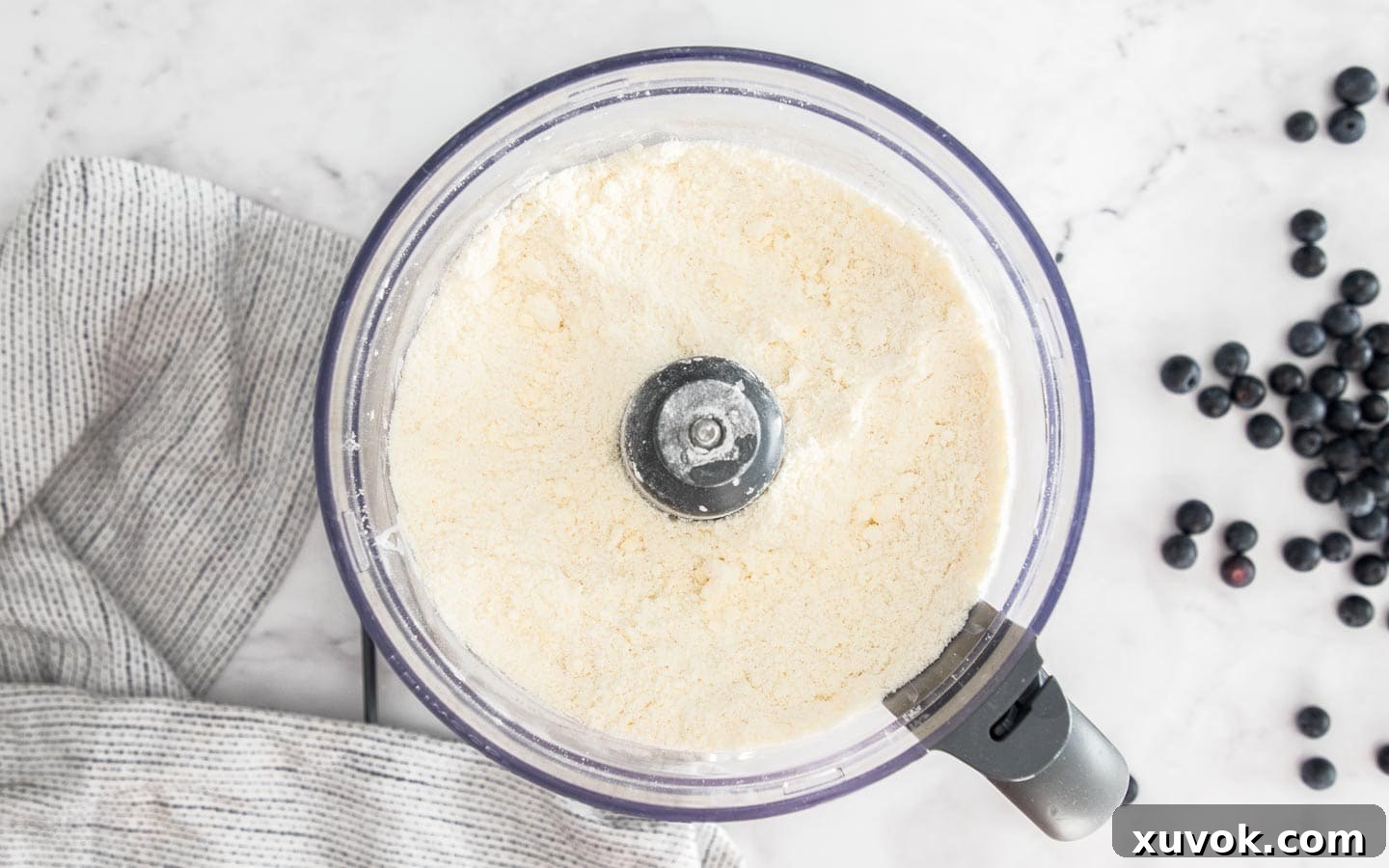 The pastry mixture in a food processor, showing the initial sandy texture before water is added.