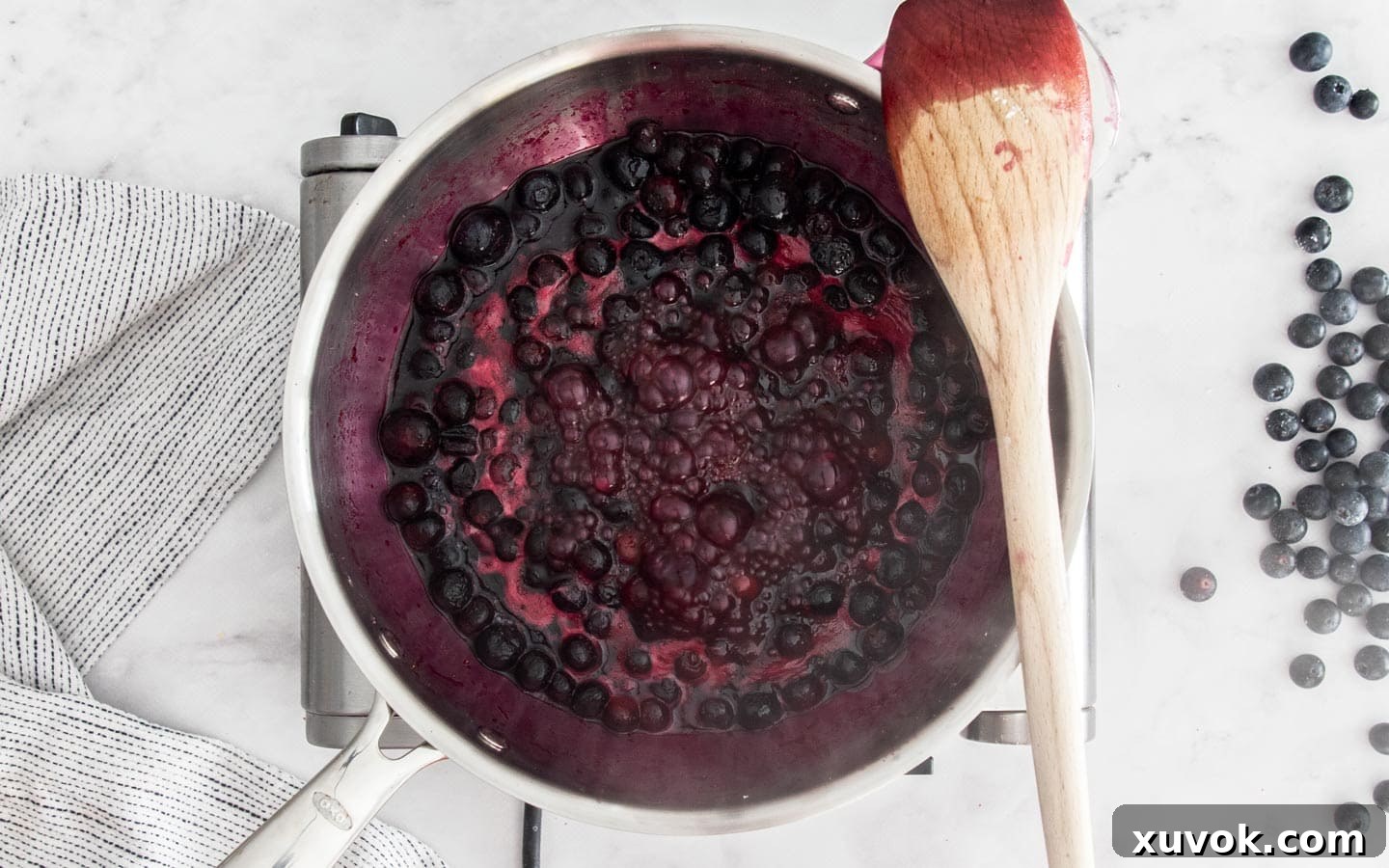 Blueberry filling simmering and bubbling in a saucepan on the stovetop.