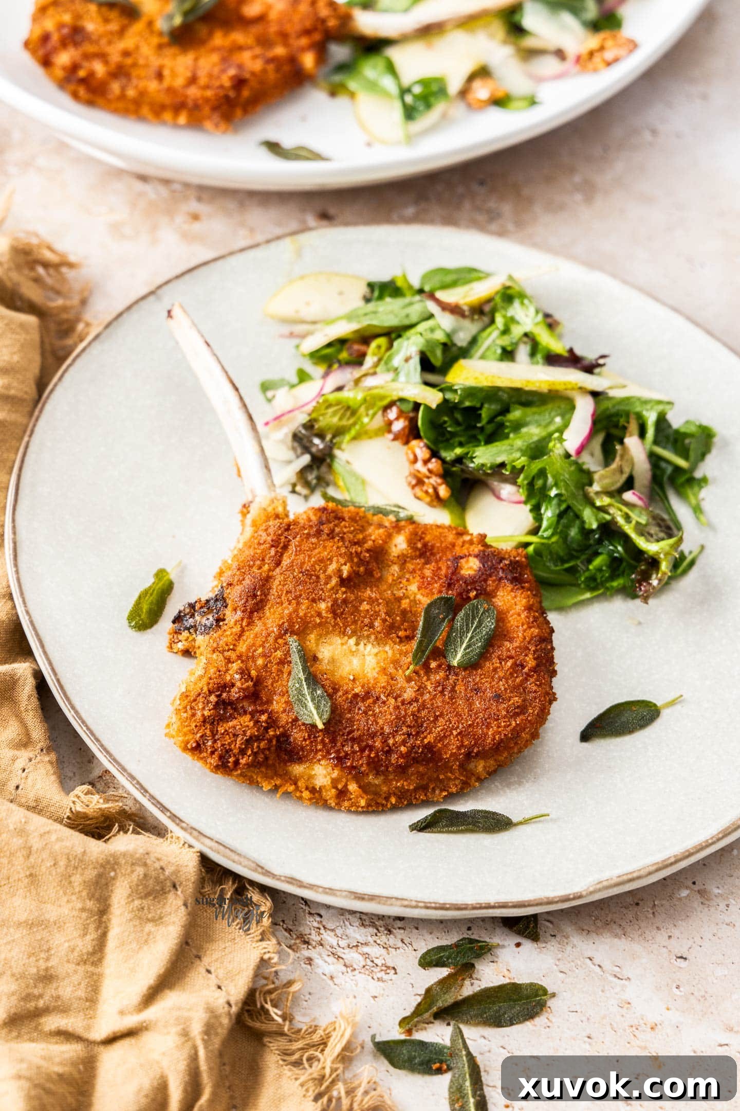 A perfectly fried pork cotoletta served on a dinner plate with a vibrant side salad, ready to enjoy.