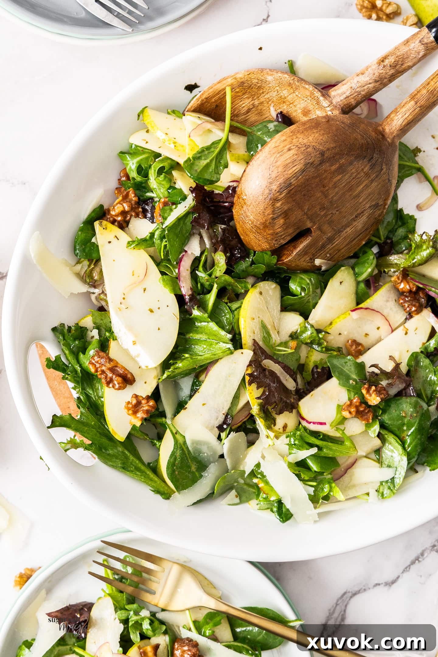 The salad in a bowl with wooden salad servers, showcasing fresh ingredients and vibrant colors.