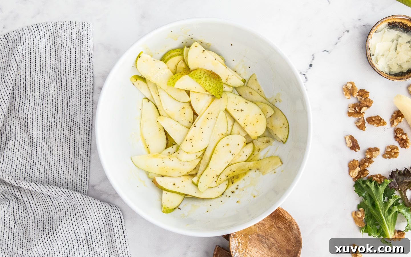 Sliced pears being dressed with the homemade Italian dressing in a mixing bowl.