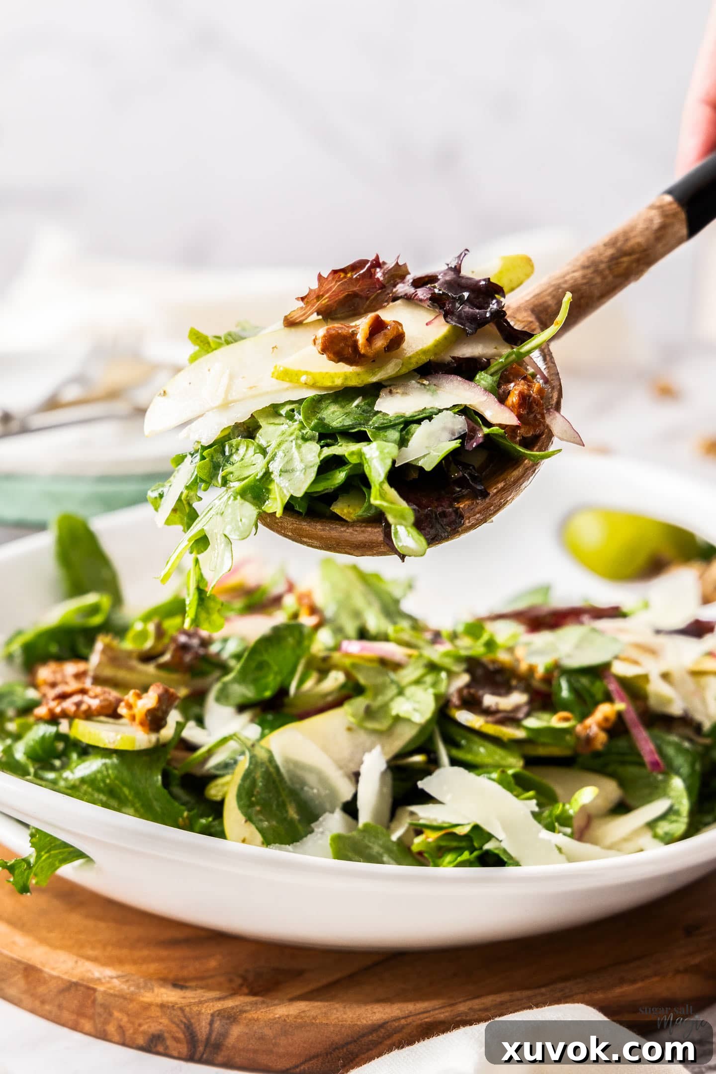 A scoop of pear & walnut salad on a wooden salad spoon, ready to be enjoyed.