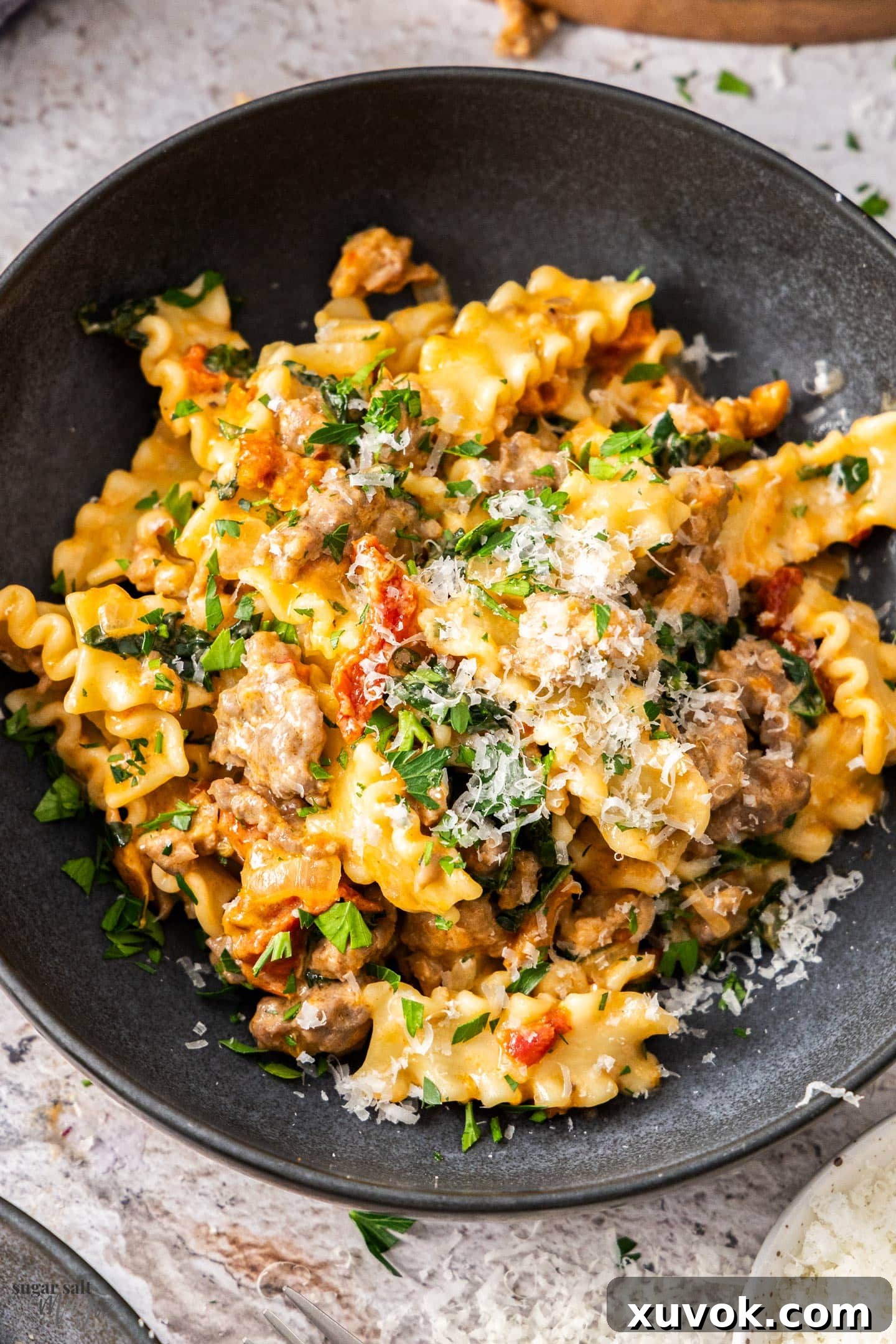 Top down view of a bowl filled with creamy fennel sausage pasta, garnished with fresh herbs, showcasing its rich texture.