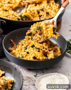 A serving spoon adding some of the pasta dish to a bowl, showcasing its rich texture and ingredients.