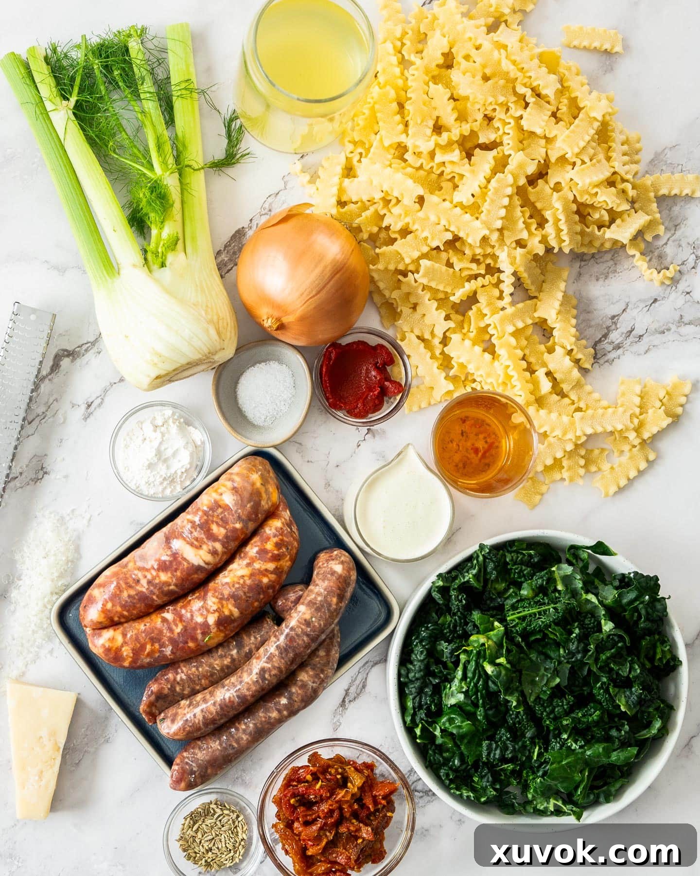 A curated selection of fresh and packaged ingredients for sausage fennel pasta, including whole fennel, sun-dried tomatoes, and pasta.