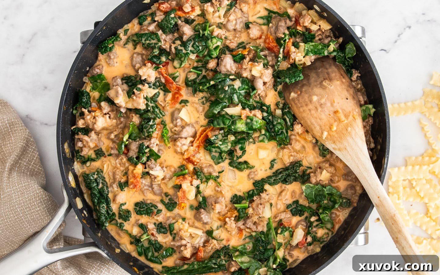 The pan with Tuscan kale added to the creamy sauce, wilting into the mixture.