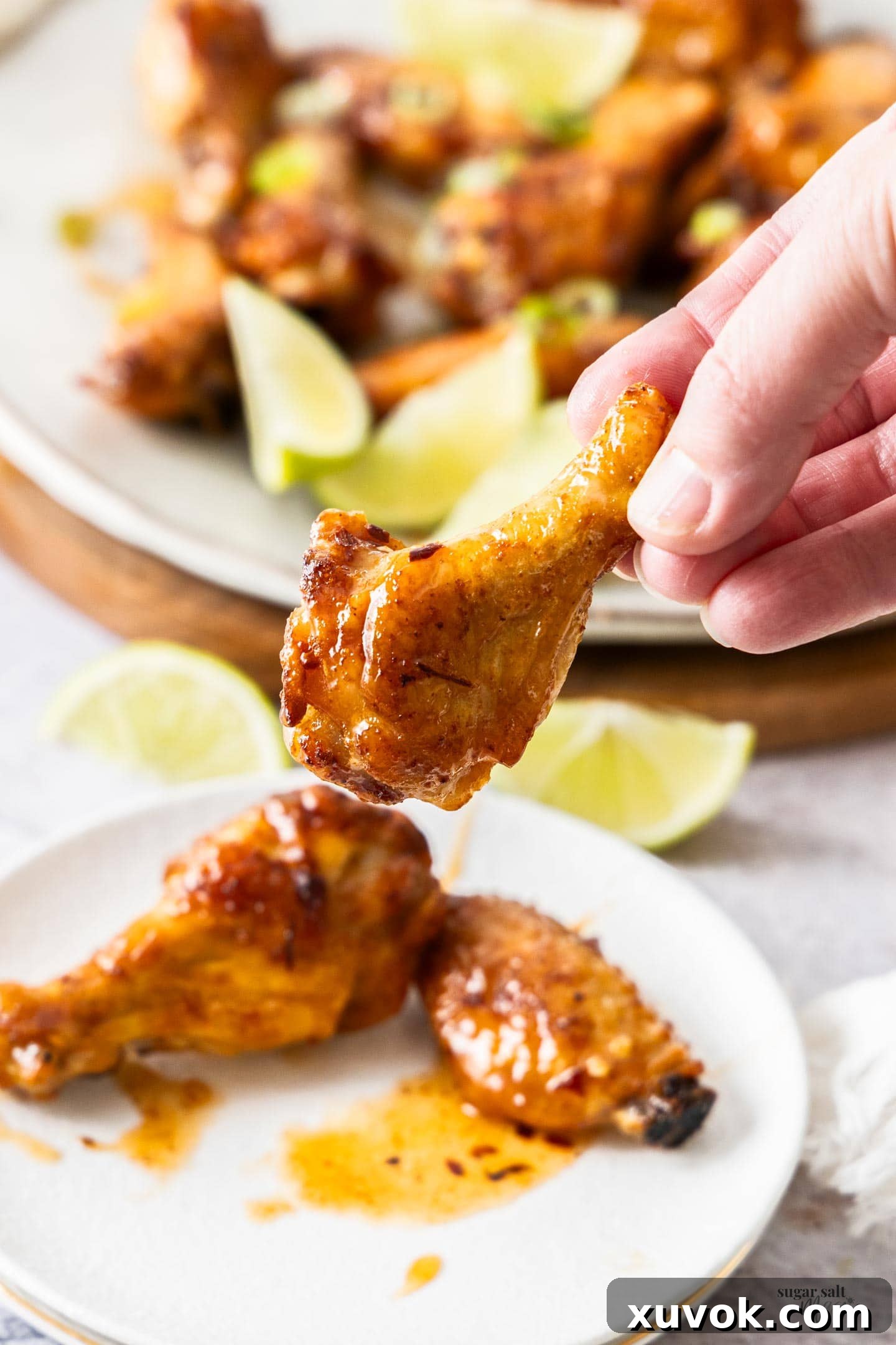 A hand holding a hot honey wing drumette.
