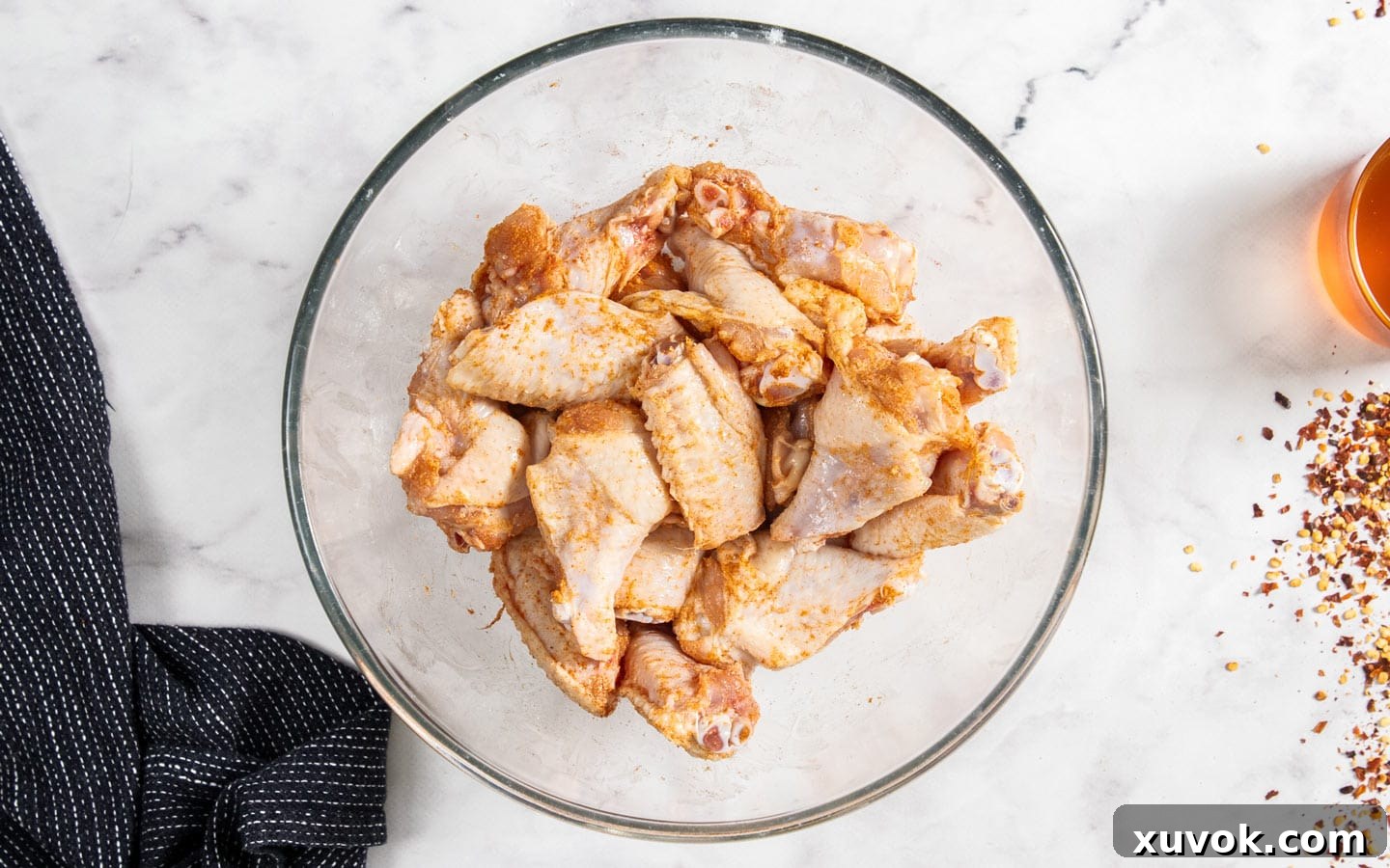The seasoned wing pieces in a glass mixing bowl.