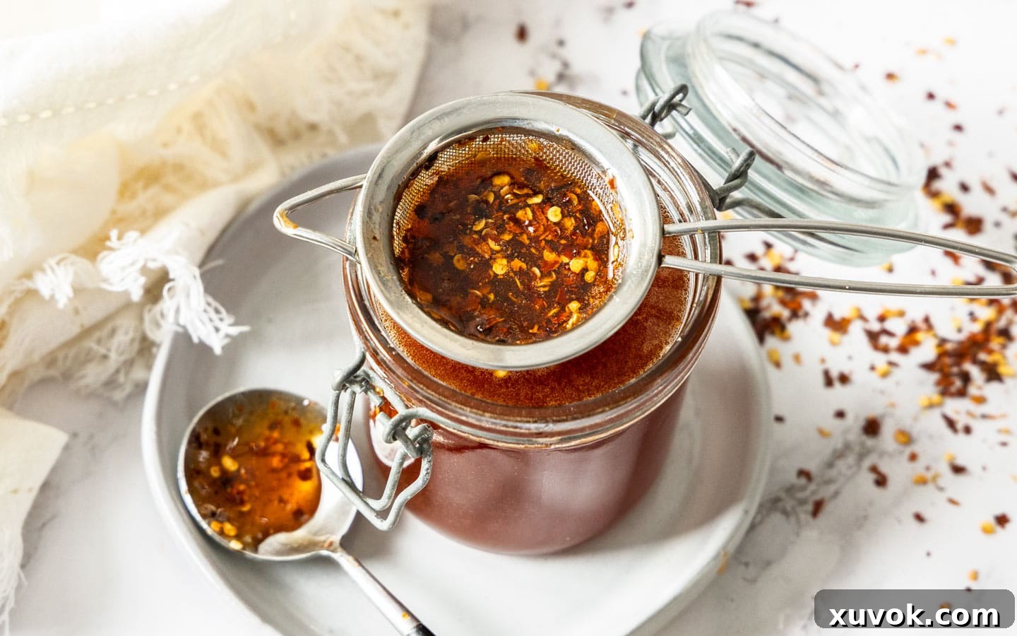 Chilli flakes in a strainer over a jar.