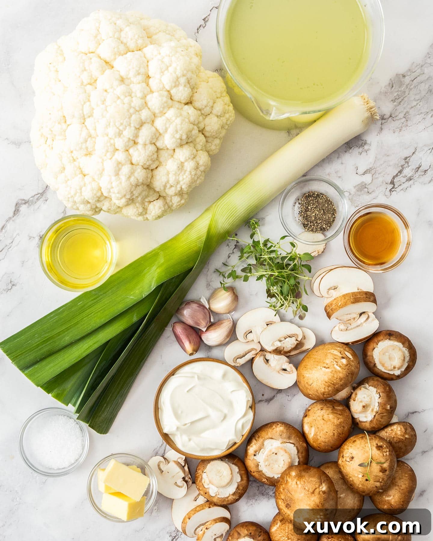 Fresh ingredients for making creamy mushroom cauliflower soup, including whole cauliflower, mushrooms, leek, garlic, and fresh thyme.