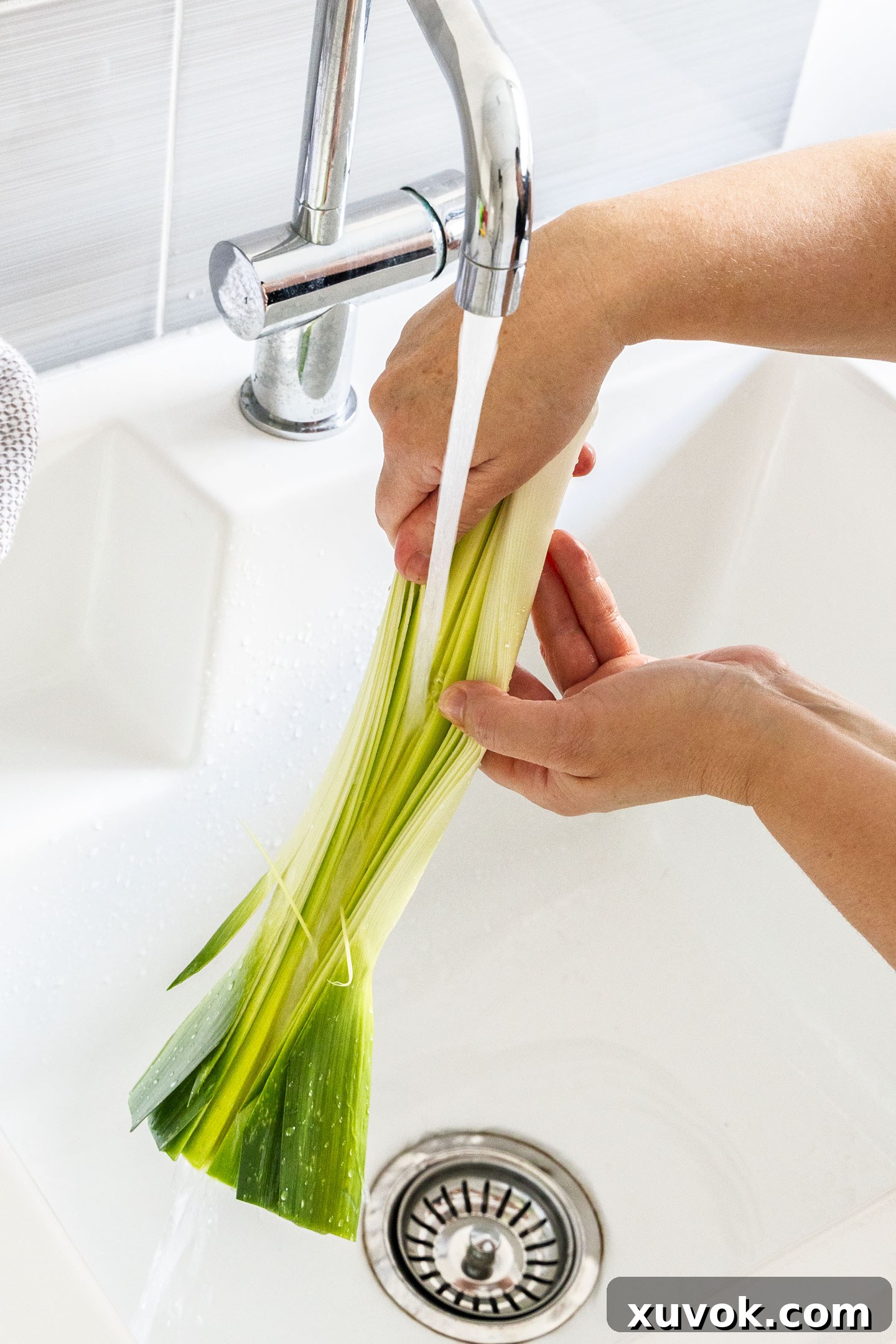 Fanning the layers of a leek under running water, ensuring all dirt is removed from deep within the folds.