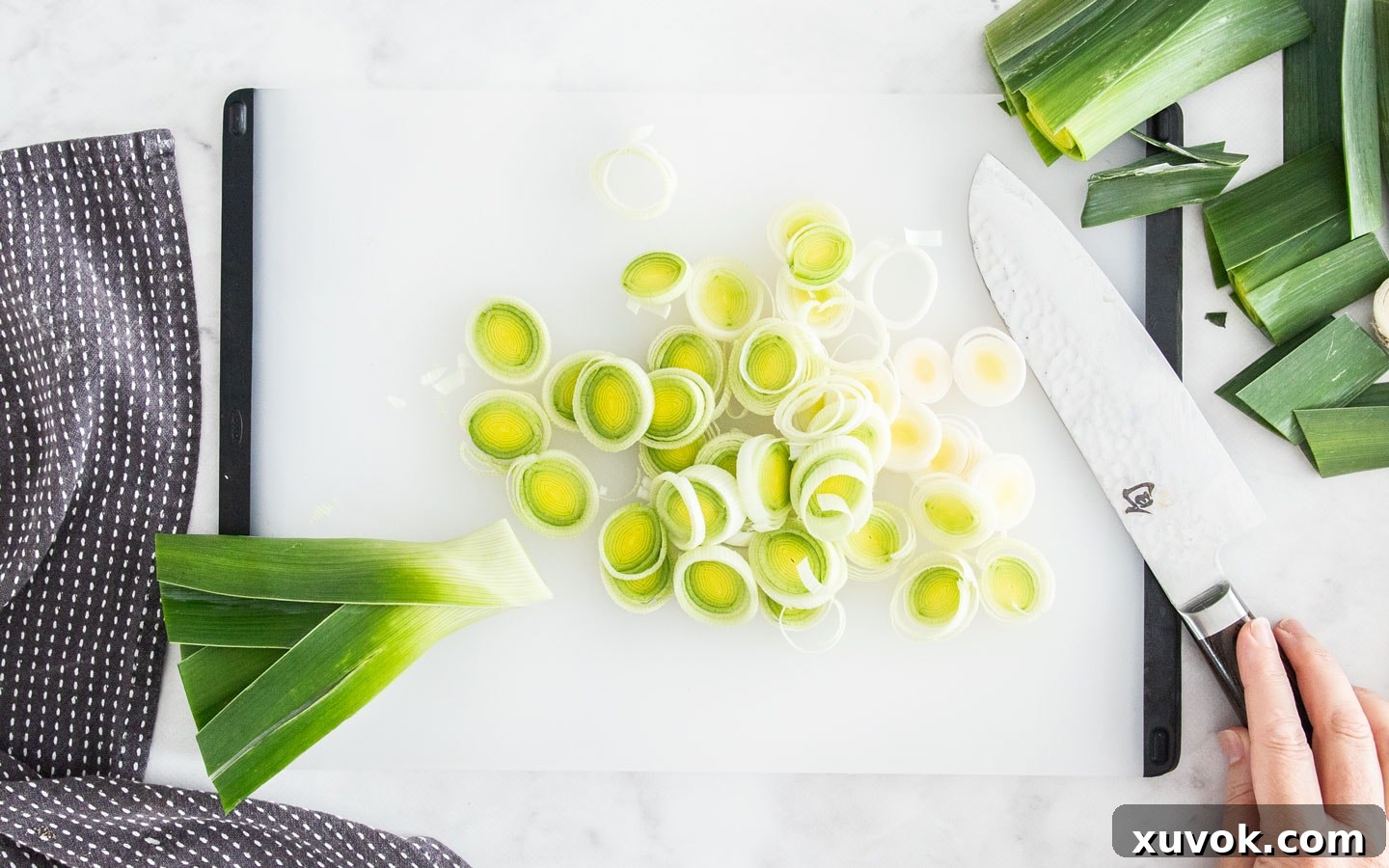 Rings of thinly sliced leeks arranged on a chopping board, prepared for the washing process.