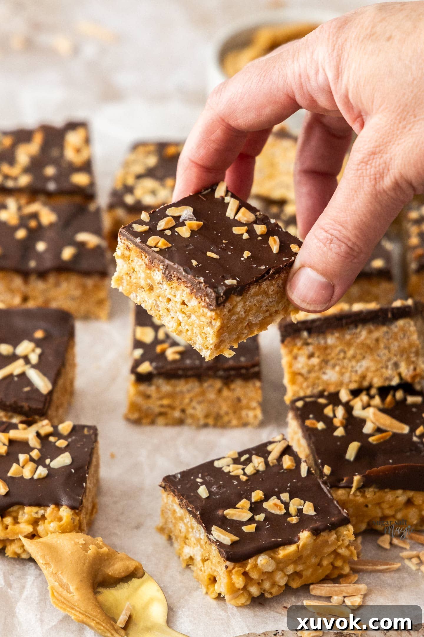 A hand holding a single chocolate peanut butter rice crispy bar, showing its inviting texture and delicious layers.