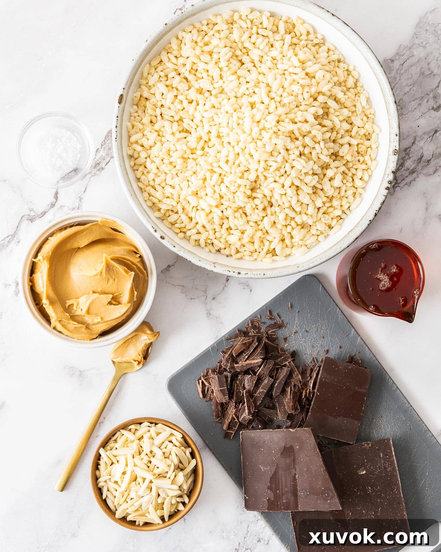 A flat lay of ingredients for chocolate peanut butter rice crispy bars, including puffed rice, peanut butter, chocolate, and almonds.