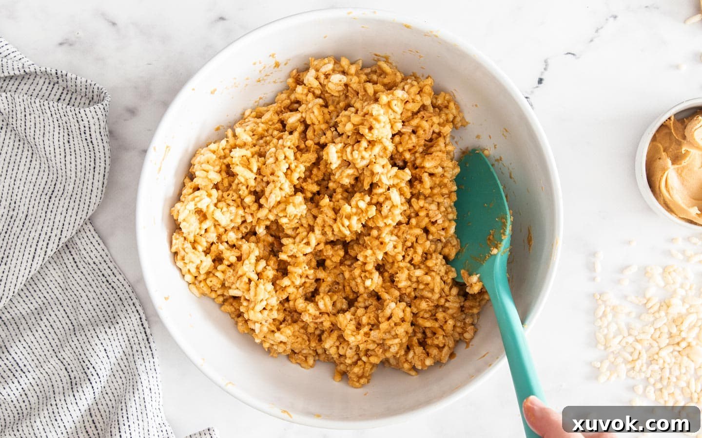 Close-up of the peanut butter and puffed rice mixture, evenly coated and glistening.