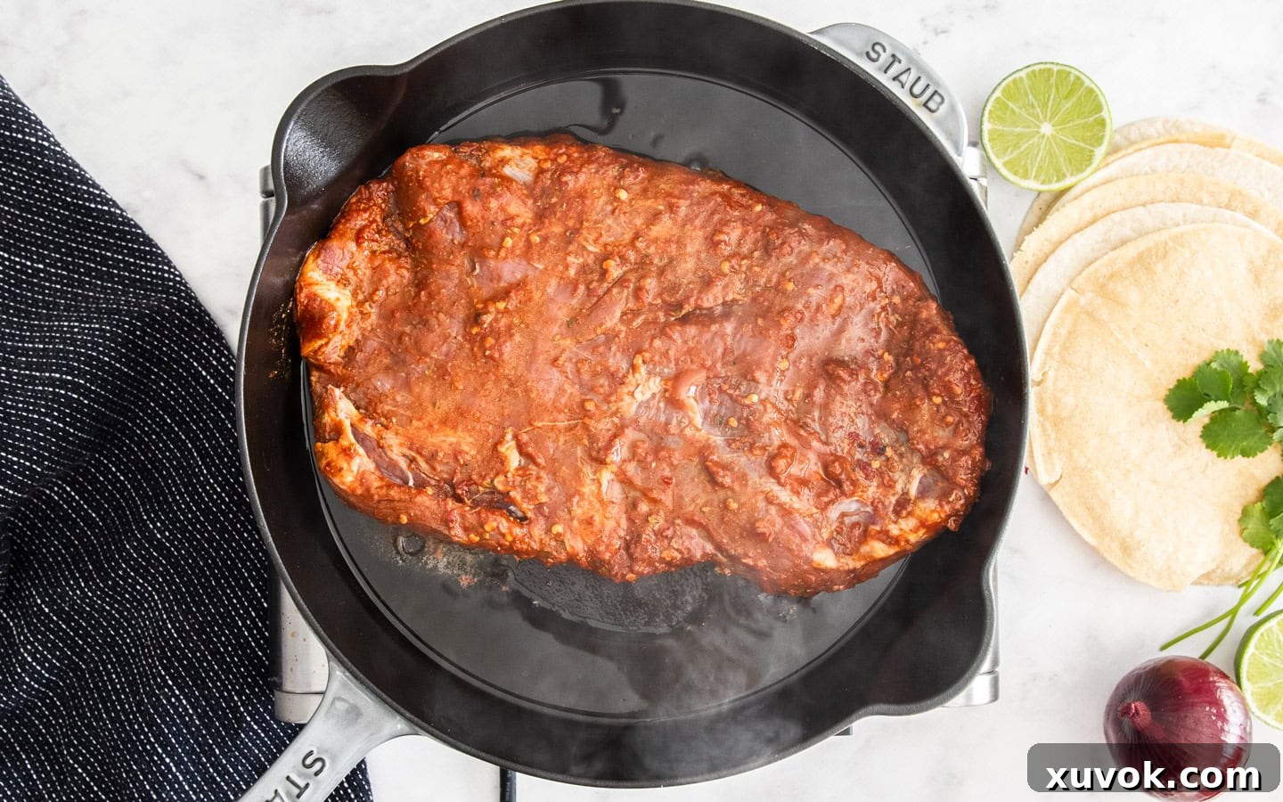 The flank steak cooking in a skillet.