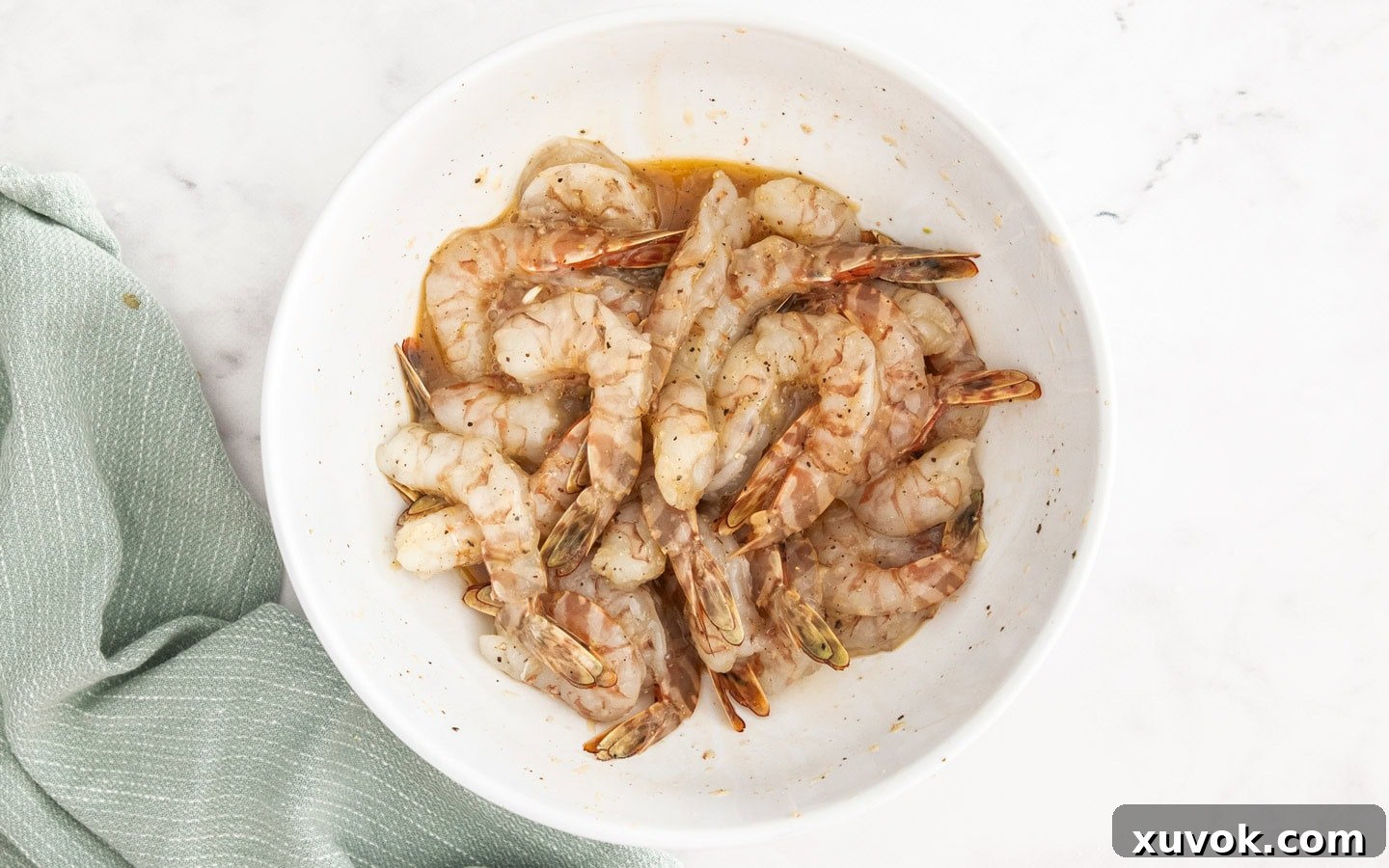 Prawns in a bowl mixed with egg, garlic, salt, and pepper seasoning.