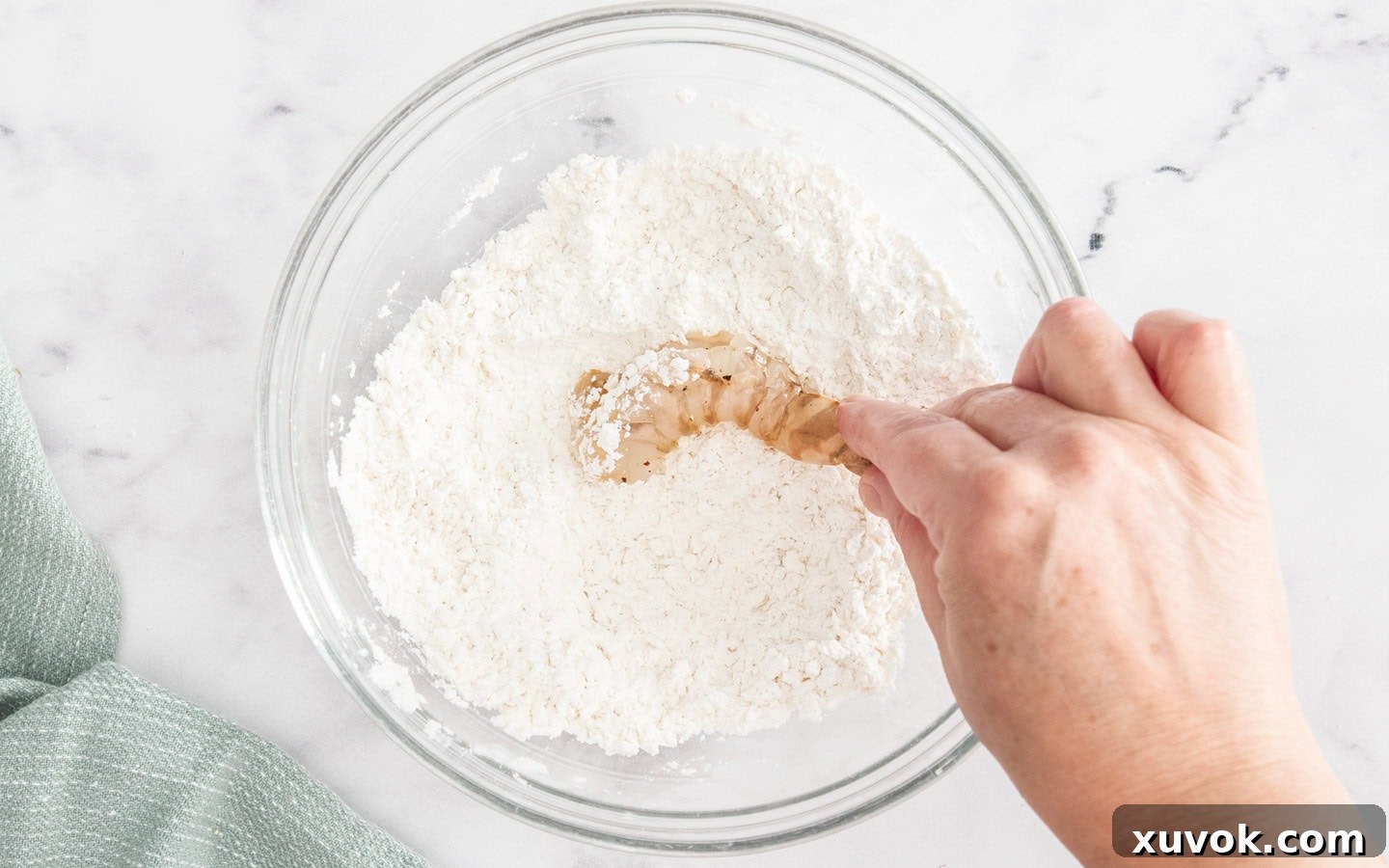 Dipping a seasoned prawn into the dry flour and panko crumb coating mixture.