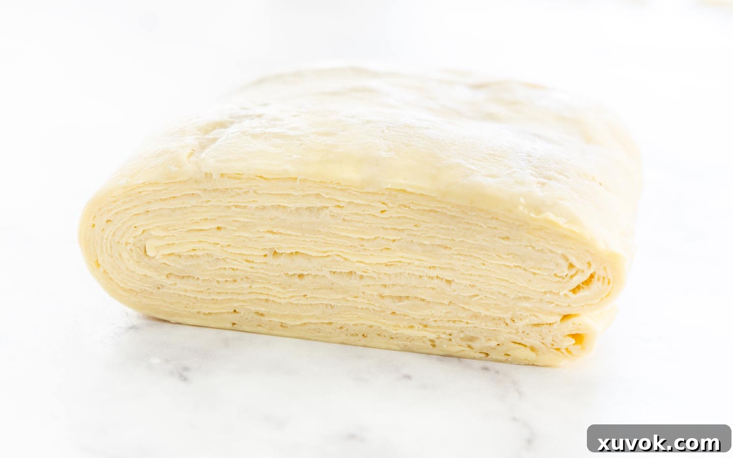 A profile view of the chilled Danish dough, clearly showing the distinct, beautiful layers developed through the lamination process.
