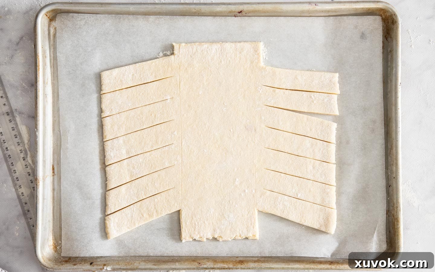 The Danish dough shaped and trimmed, with top and bottom strips removed, ready to receive the filling and begin braiding.