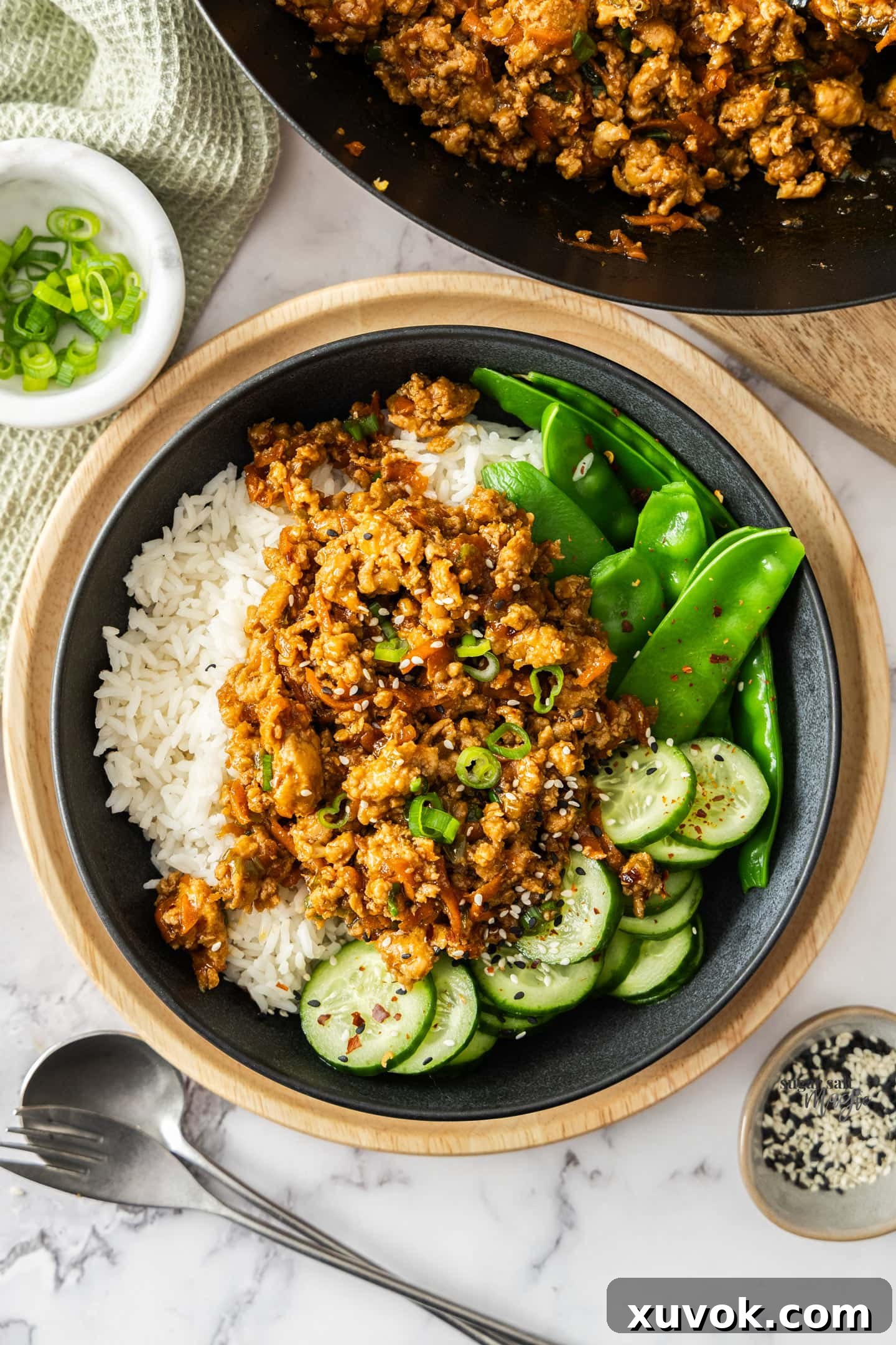 Top down view of the chicken stir fry in a bowl with rice and greens, highlighting its appealing presentation.