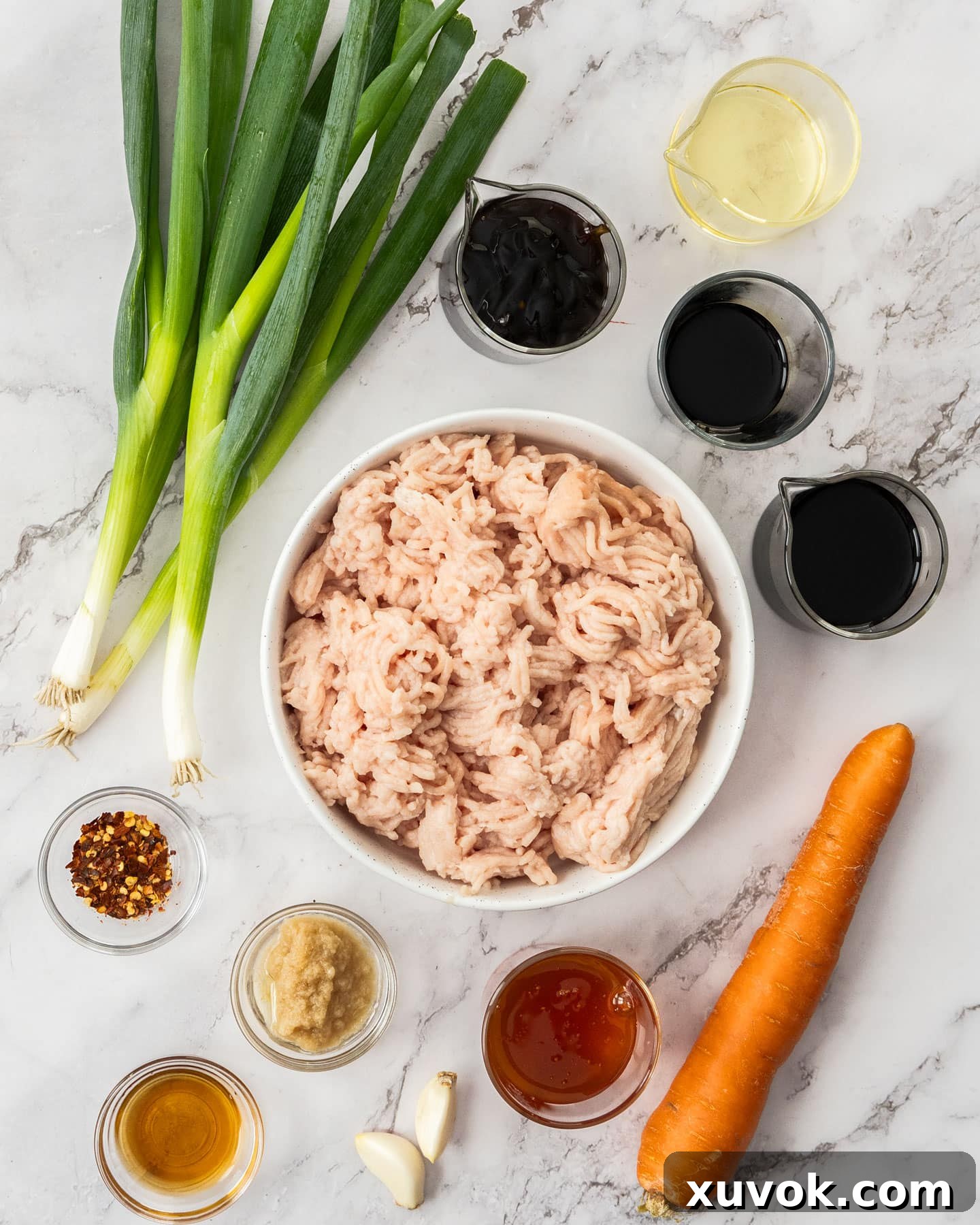 Various ingredients for sticky chicken mince stir fry meticulously arranged on a stylish marble surface.