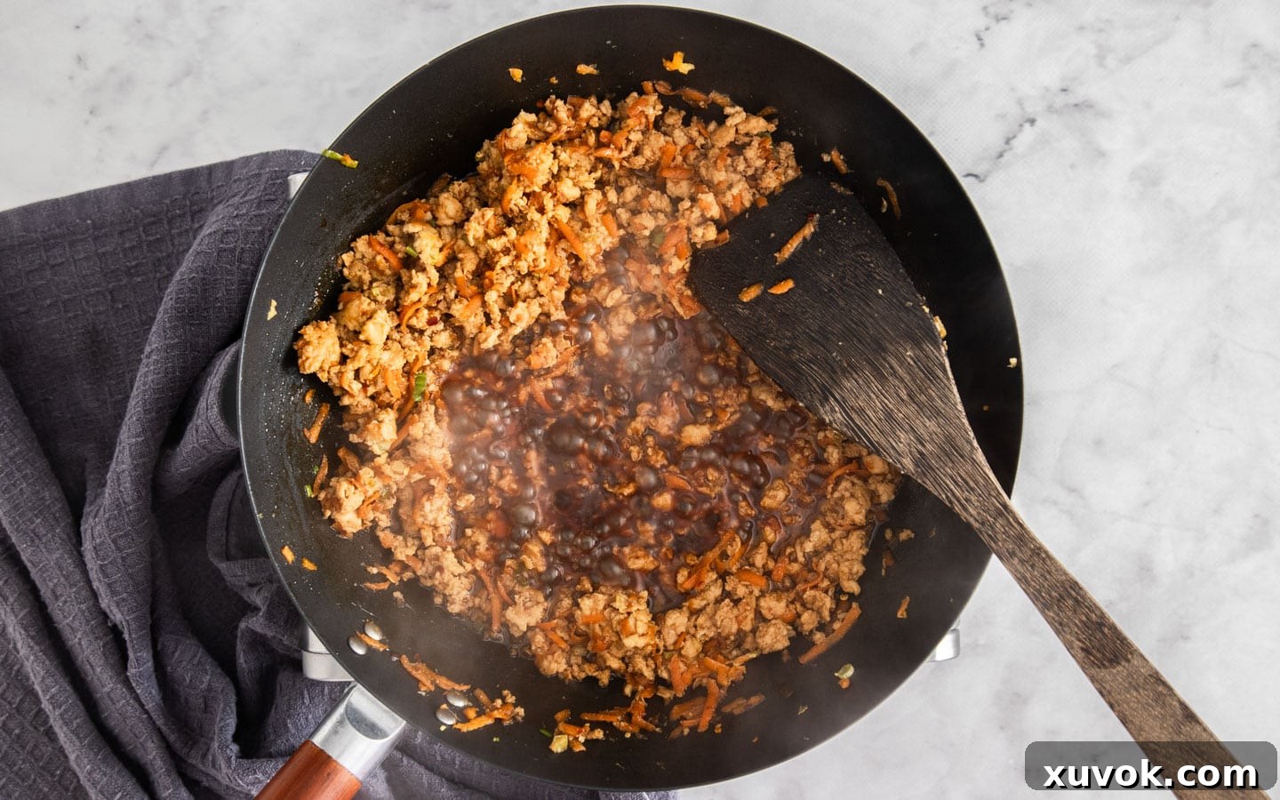 The rich, glossy sauce bubbling and reducing in the wok, creating a perfectly sticky coating for the chicken.