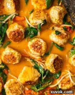 Top down view, closeup of the meatballs in the red curry sauce.