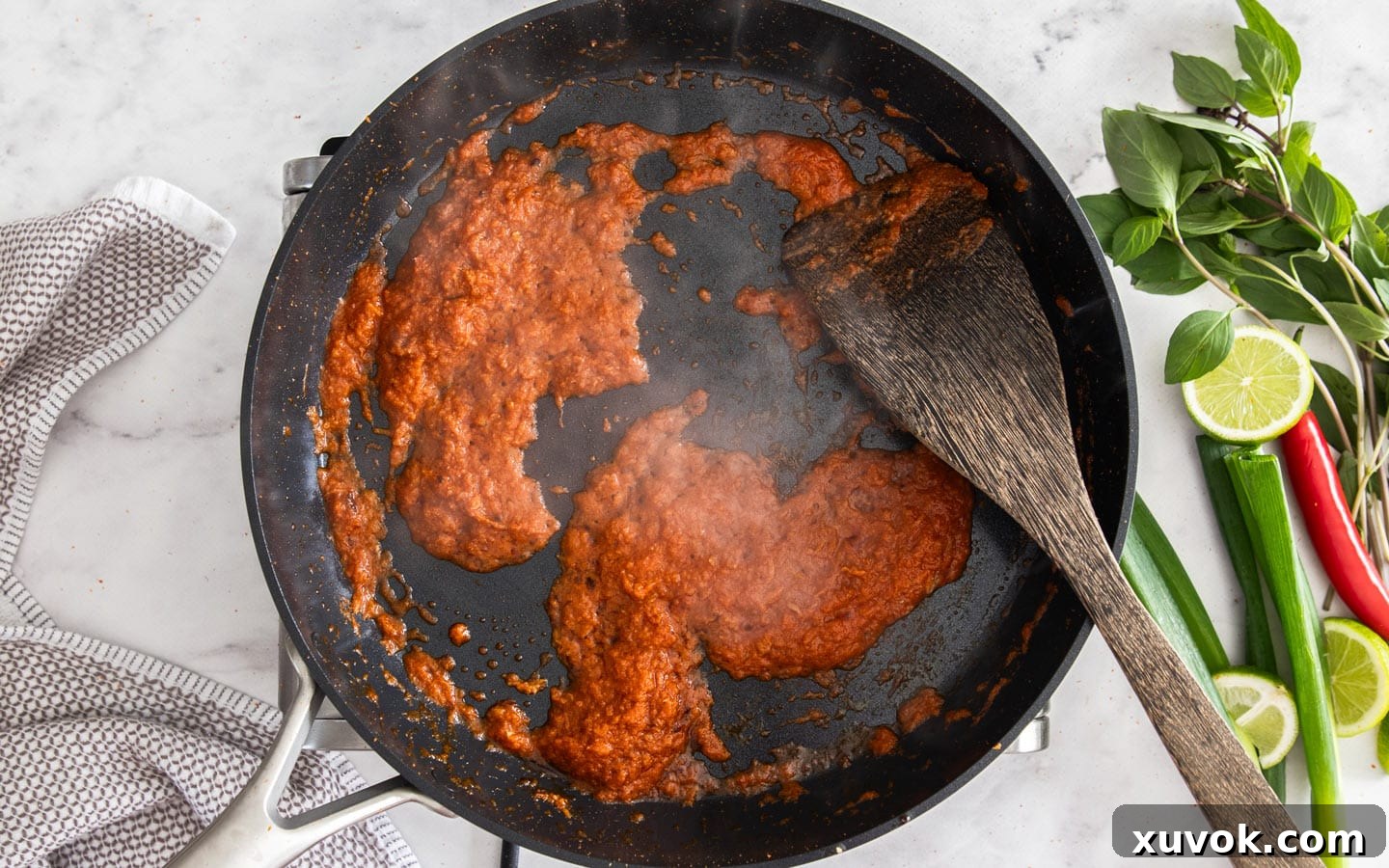 The curry paste and aromatics frying in a pan.