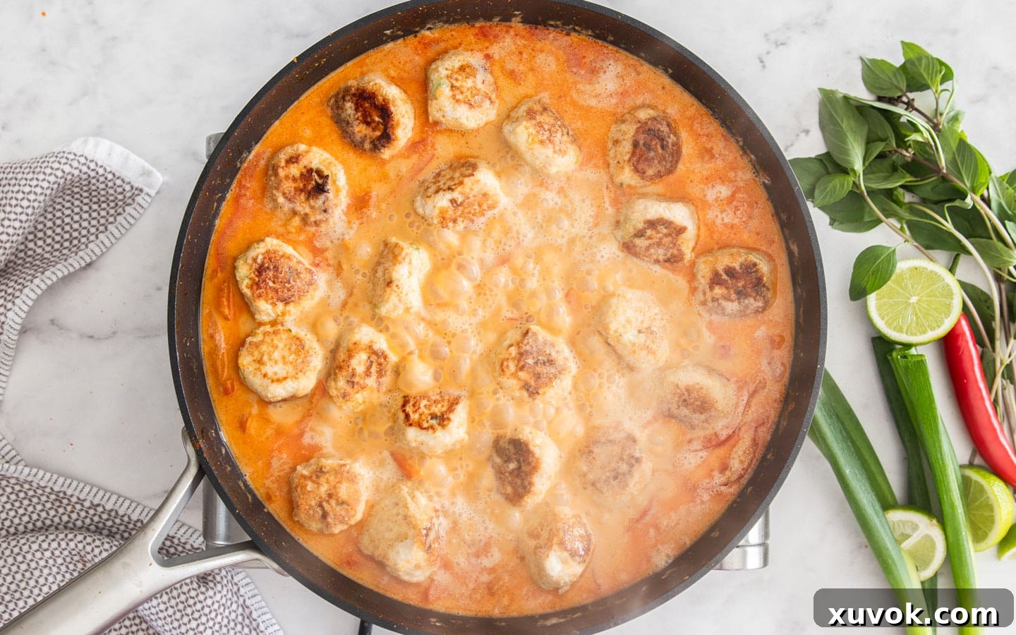 The meatballs in the bubbling sauce in a pan.