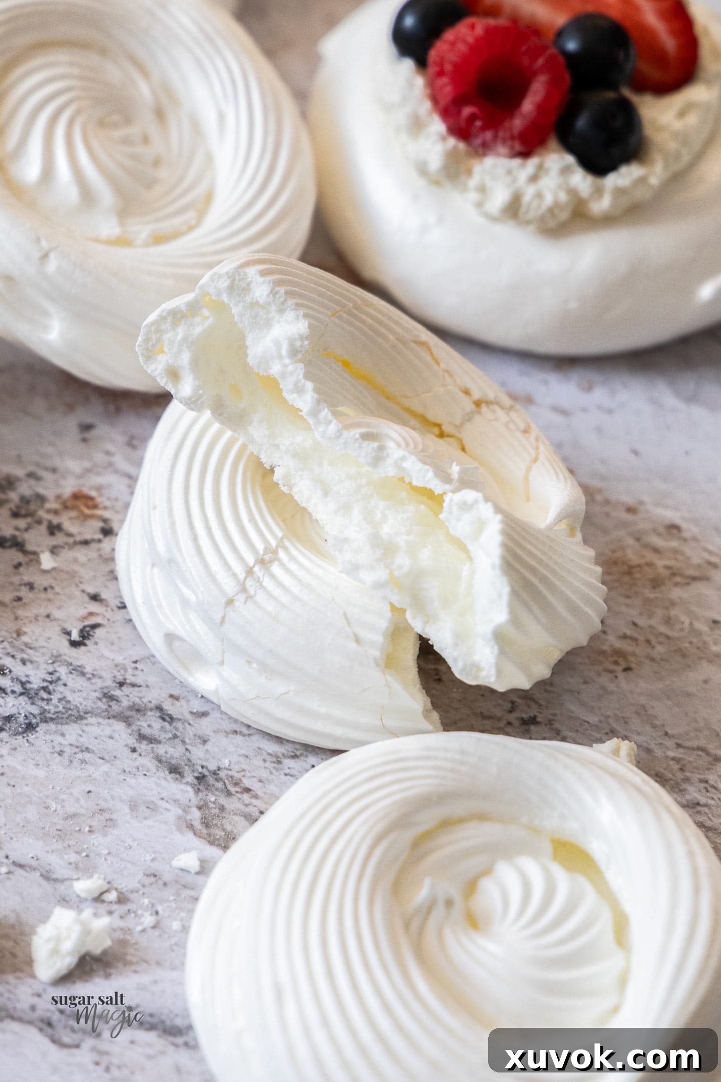 A meringue shell broken in half to reveal its perfectly crisp and hollow interior, demonstrating successful baking.