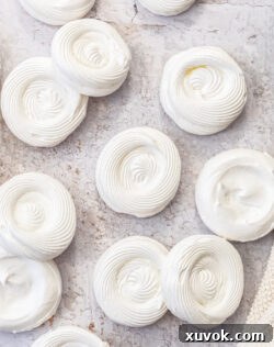 Top down view of a batch of perfectly formed meringue shells, showcasing their light and airy texture.