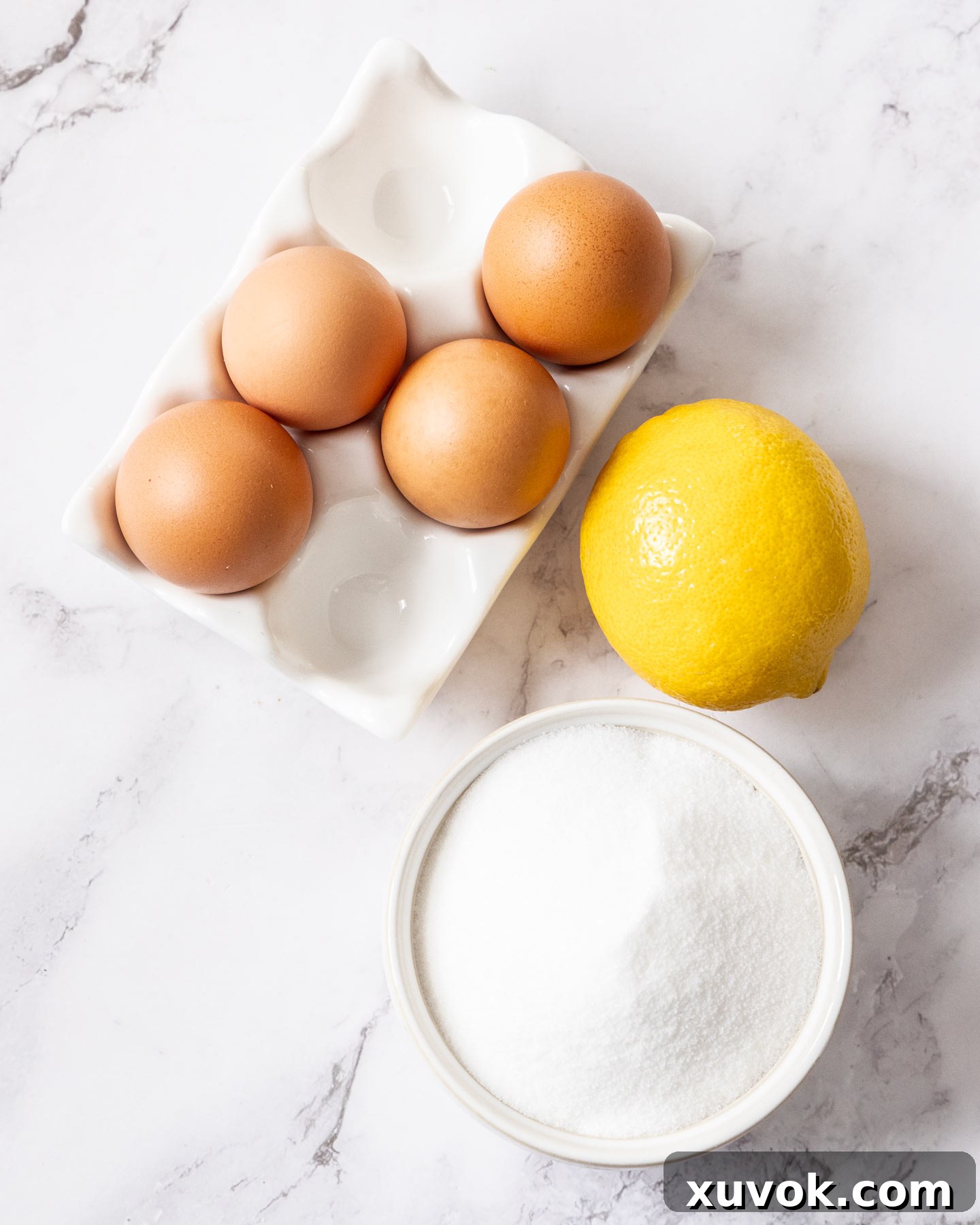 Ingredients for meringue nests neatly arranged on a pristine marble surface, highlighting freshness and quality.