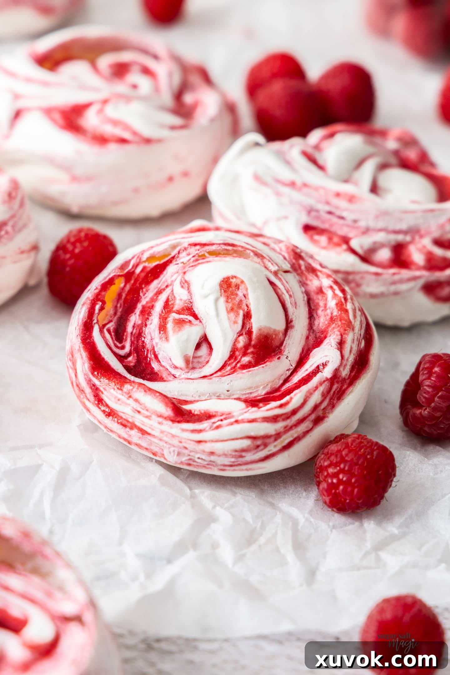 Closeup of a single raspberry meringue, showcasing its delicate texture and vibrant swirl.