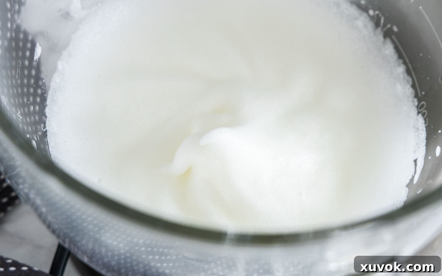 The egg whites in a mixing bowl, beautifully frothed and at the soft peak stage.