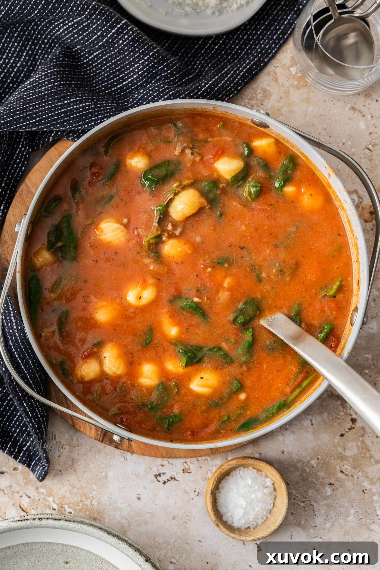 A vibrant, hearty sausage and gnocchi soup bubbling gently in a large saucepan, promising warmth and flavor.