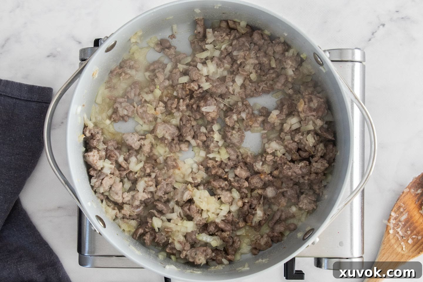 Crumbled Italian sausage, diced onions, and minced garlic sizzling and browning in a pan, filling the kitchen with enticing aromas.
