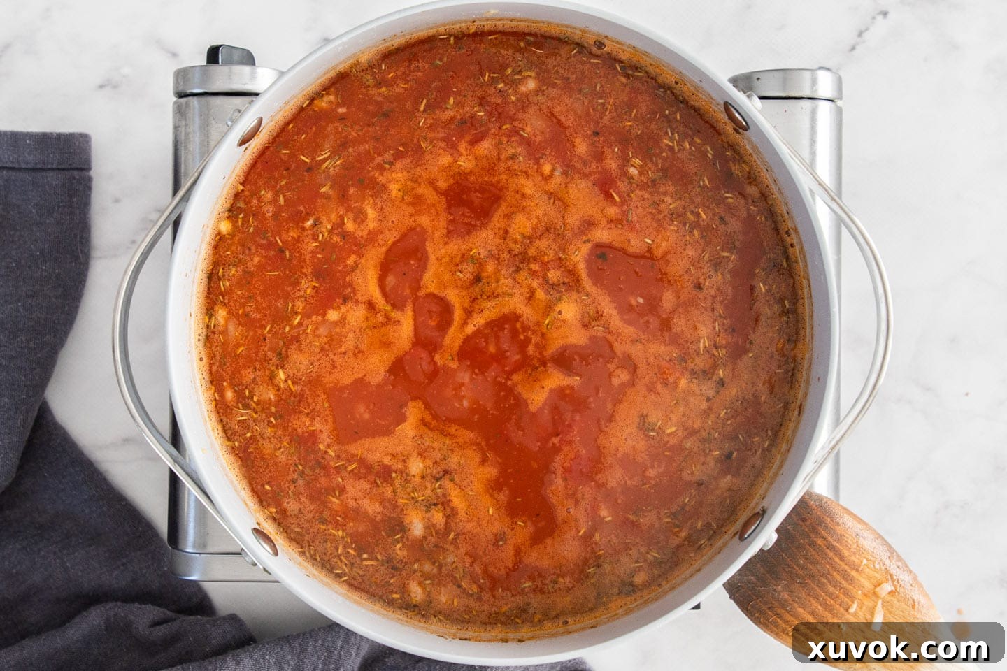 The rich, red tomato broth for the sausage gnocchi soup simmering gently in the pan, releasing fragrant steam.