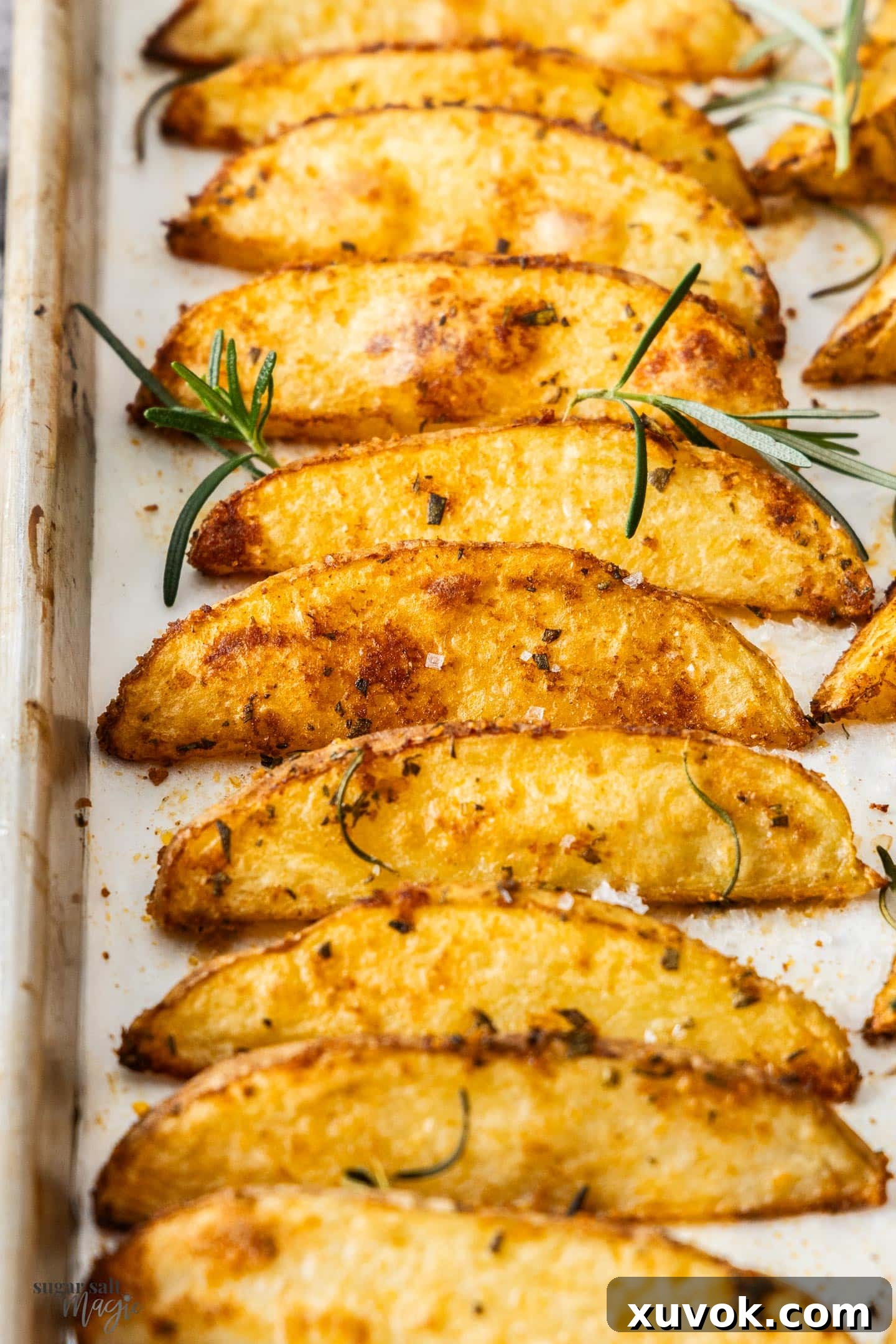 Closeup of ten crispy oven-baked potato wedges with fresh rosemary.