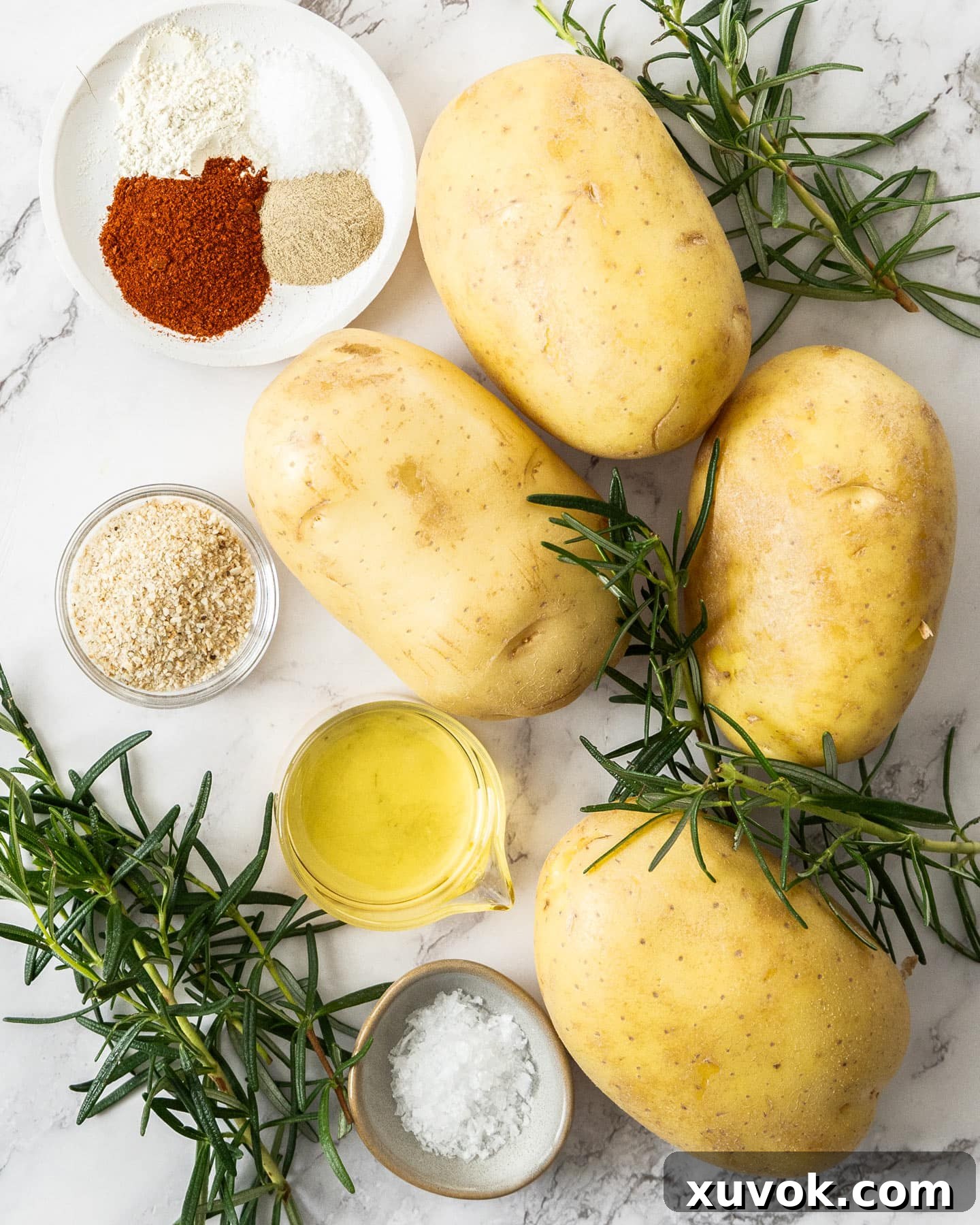 Ingredients for rosemary potato wedges laid out on a marble surface.