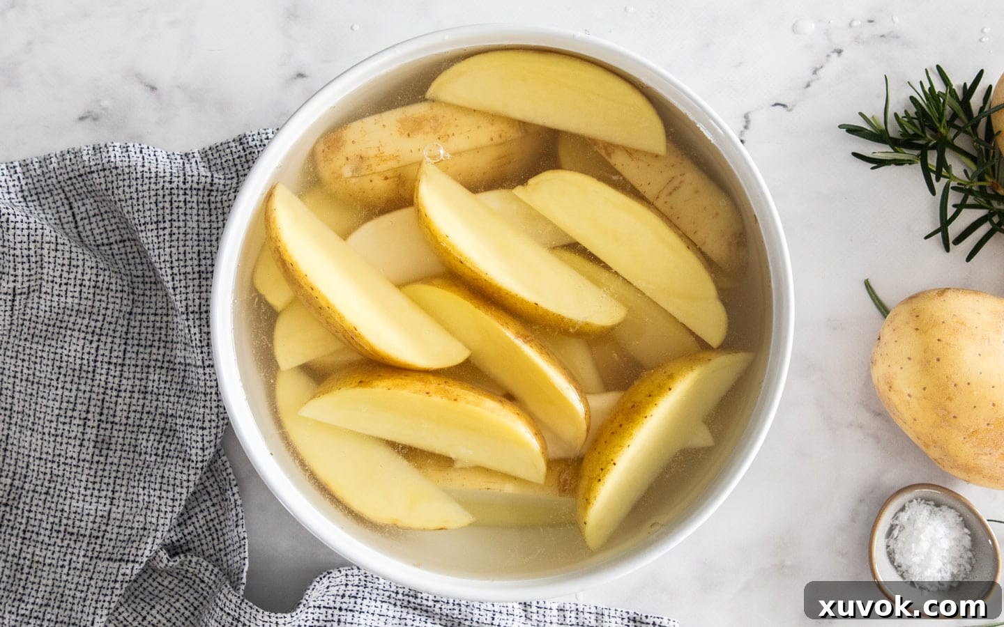 Unbaked potato wedges soaking in a bowl of water.