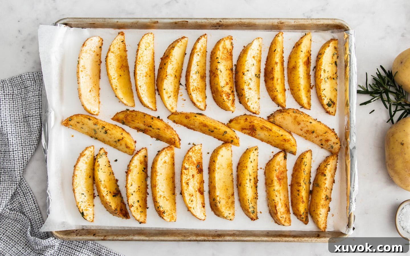 Seasoned potato wedges arranged in a single layer on a baking tray, ready for the oven.